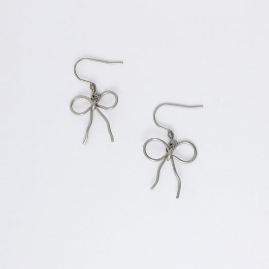 A pair of silver-toned ribbon bow drop earrings on a white background.