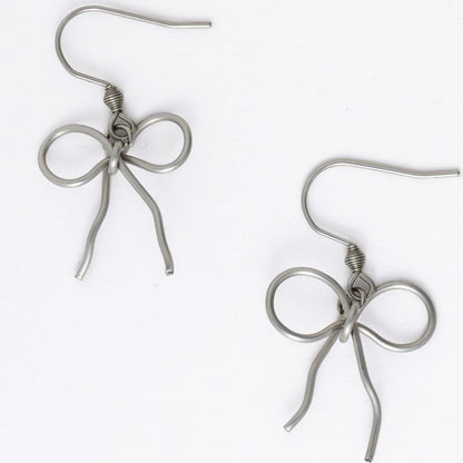 A pair of silver-toned ribbon bow drop earrings on a white background.