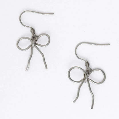 A pair of silver-toned ribbon bow drop earrings on a white background.