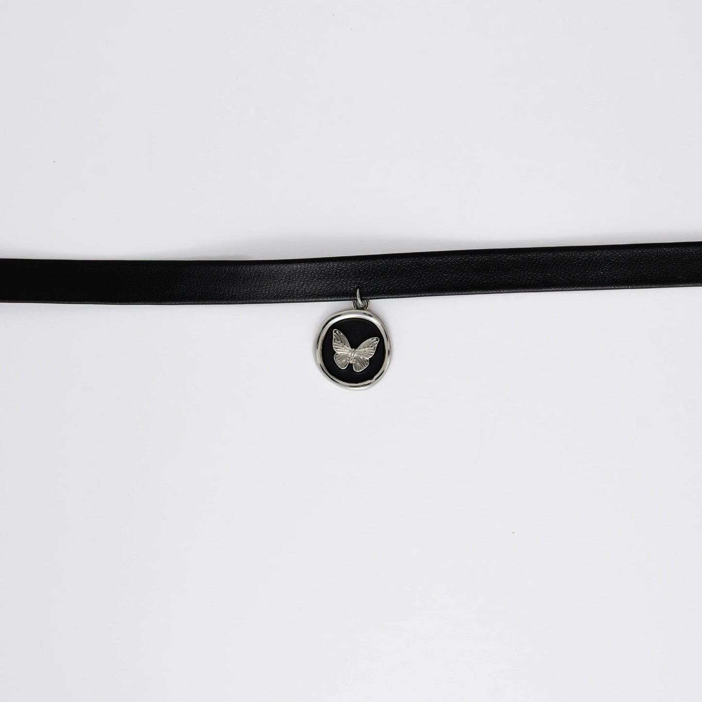 A black leather choker necklace with a central butterfly stamp pendant, displayed against a white background