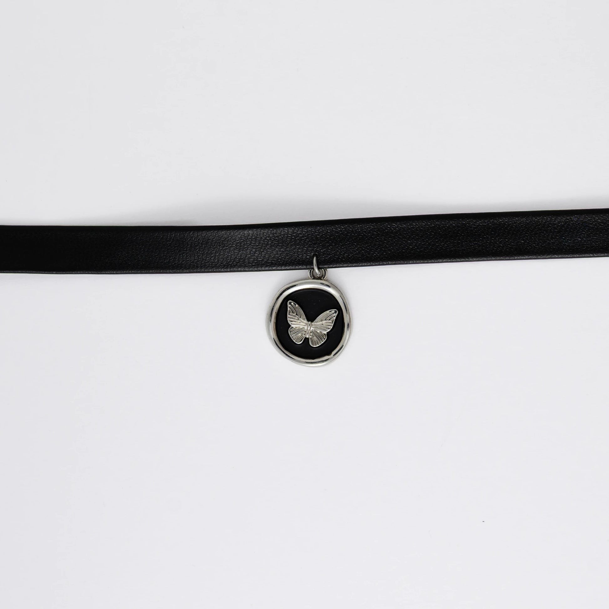 A black leather choker necklace with a central butterfly stamp pendant, displayed against a white background