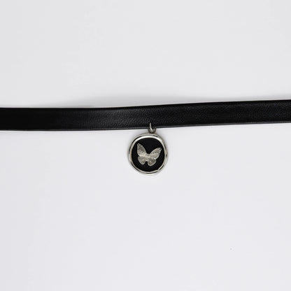 A black leather choker necklace with a central butterfly stamp pendant, displayed against a white background