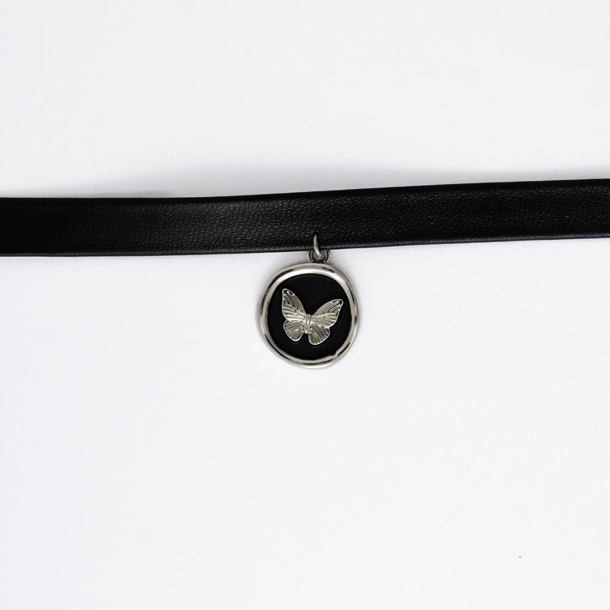 A black leather choker necklace with a central butterfly stamp pendant, displayed against a white background