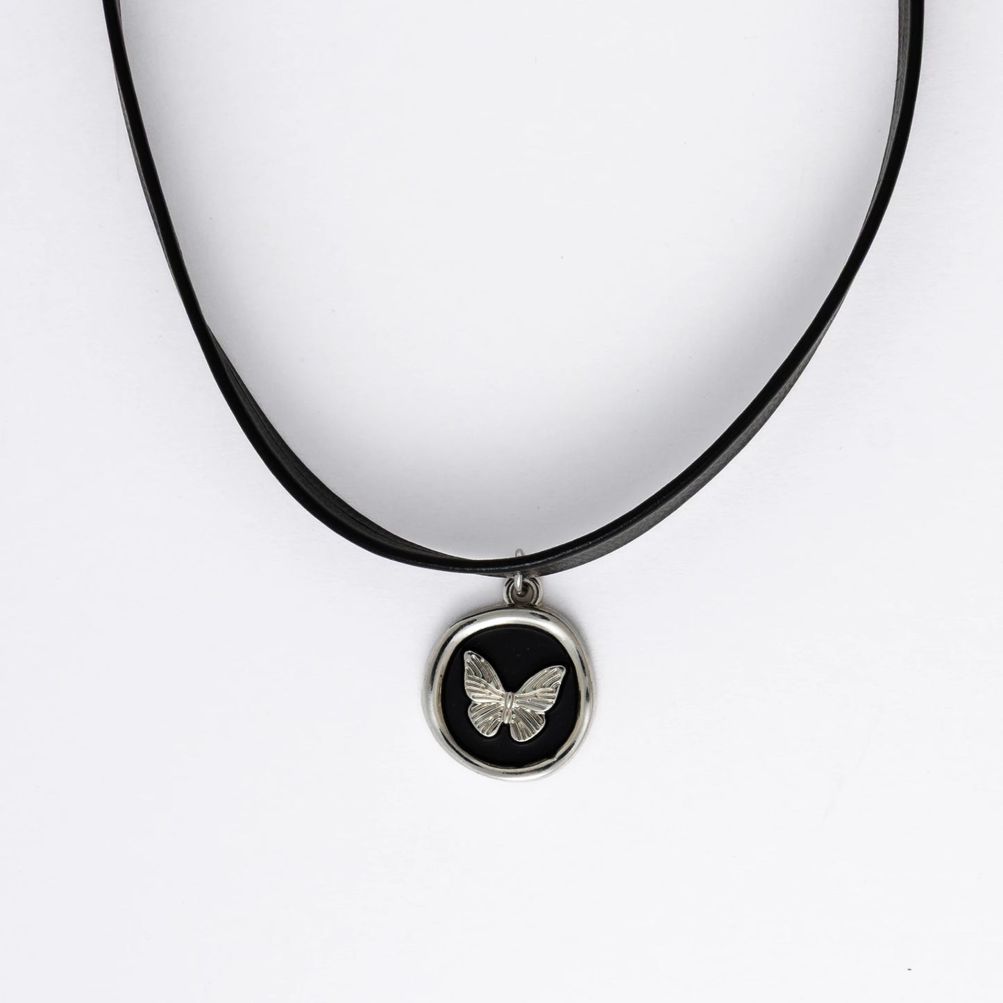 A black leather choker necklace with a central butterfly stamp pendant, displayed against a white background