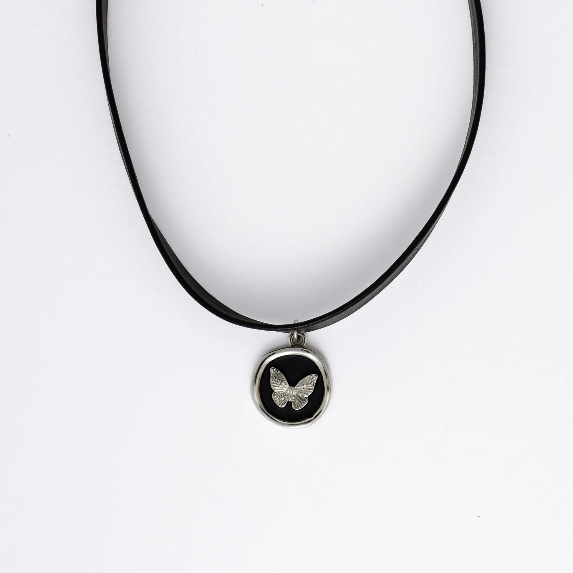 A black leather choker necklace with a central butterfly stamp pendant, displayed against a white background