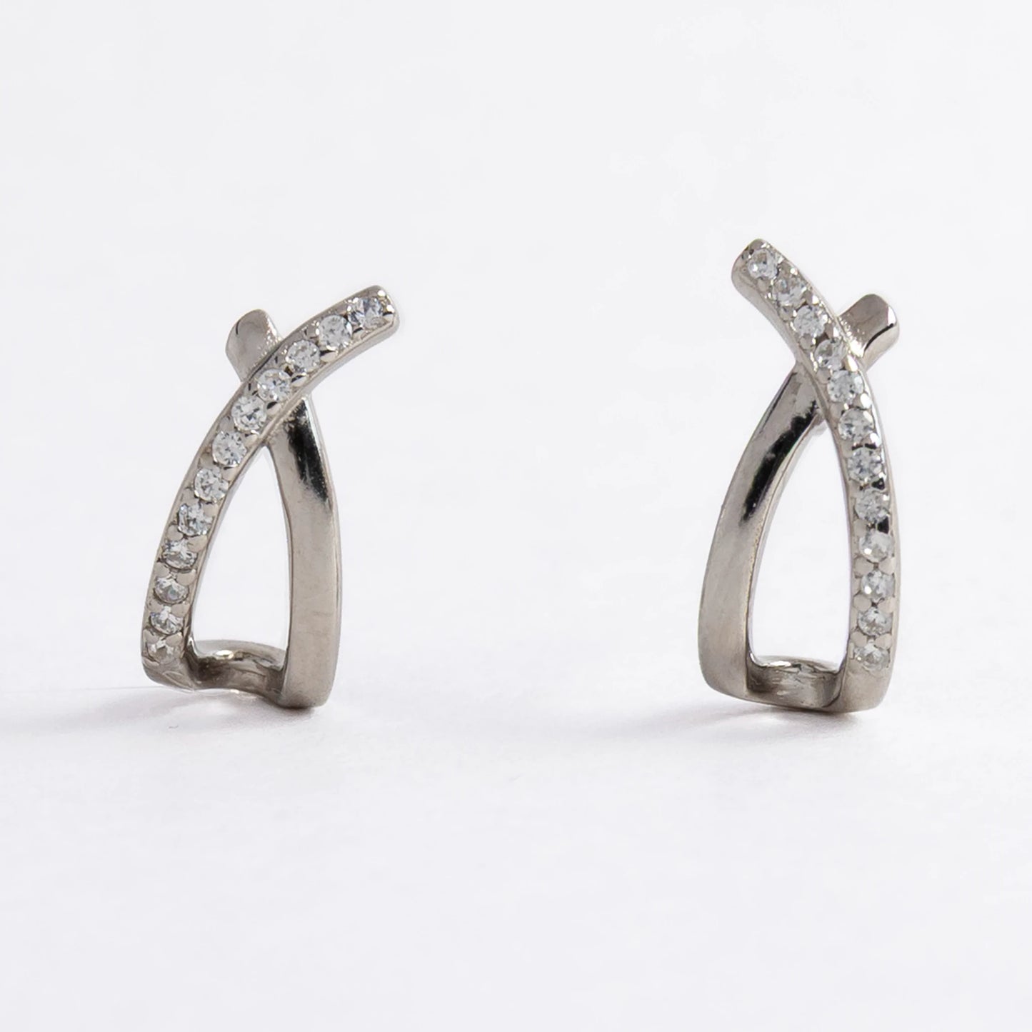 Pair of silver crossed earrings on a light gray background