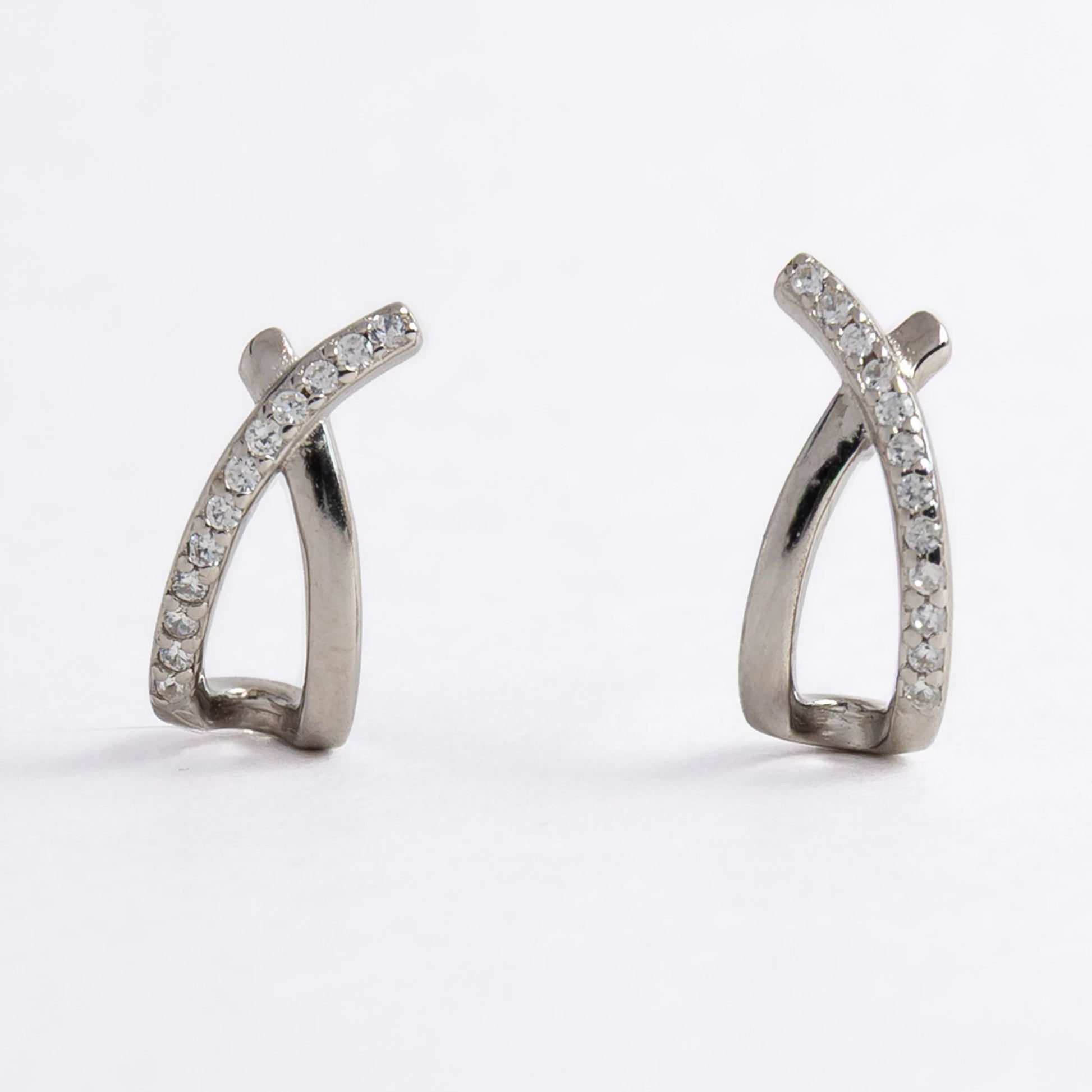 Pair of silver crossed earrings on a light gray background