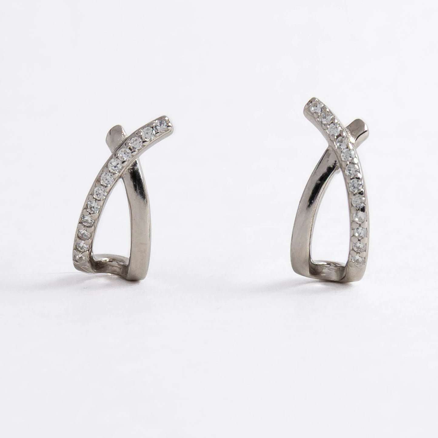 Pair of silver crossed earrings on a light gray background