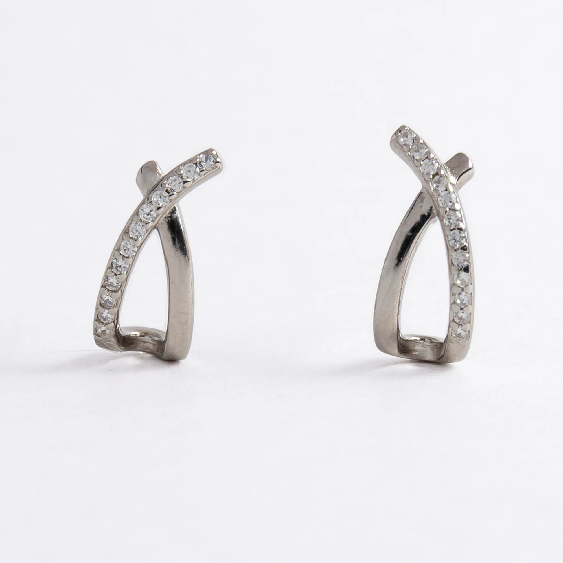 Pair of silver crossed earrings on a light gray background