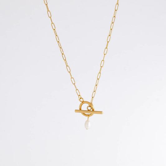 Gold paperclip necklace with toggle clasp and a pearl pendant on a light gray background