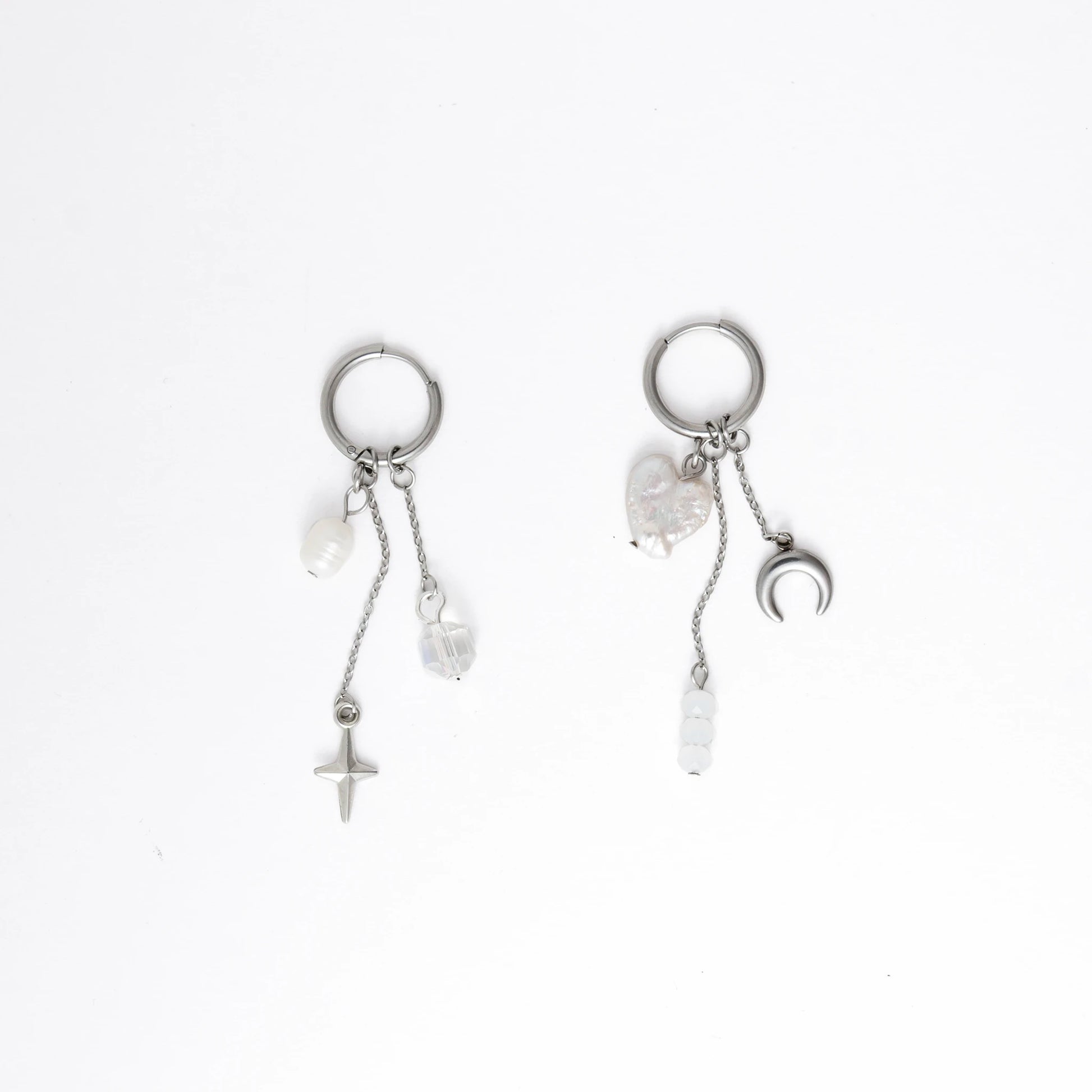 Pair of silver earrings with pearls and charms on a white background