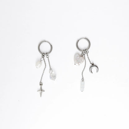 Pair of silver earrings with pearls and charms on a white background