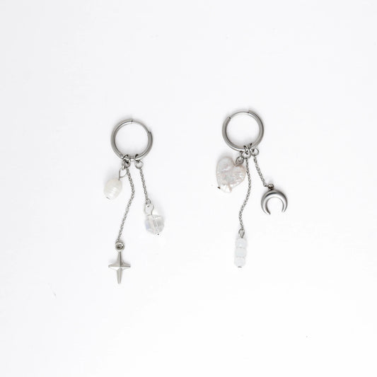 Pair of silver earrings with pearls and charms on a white background