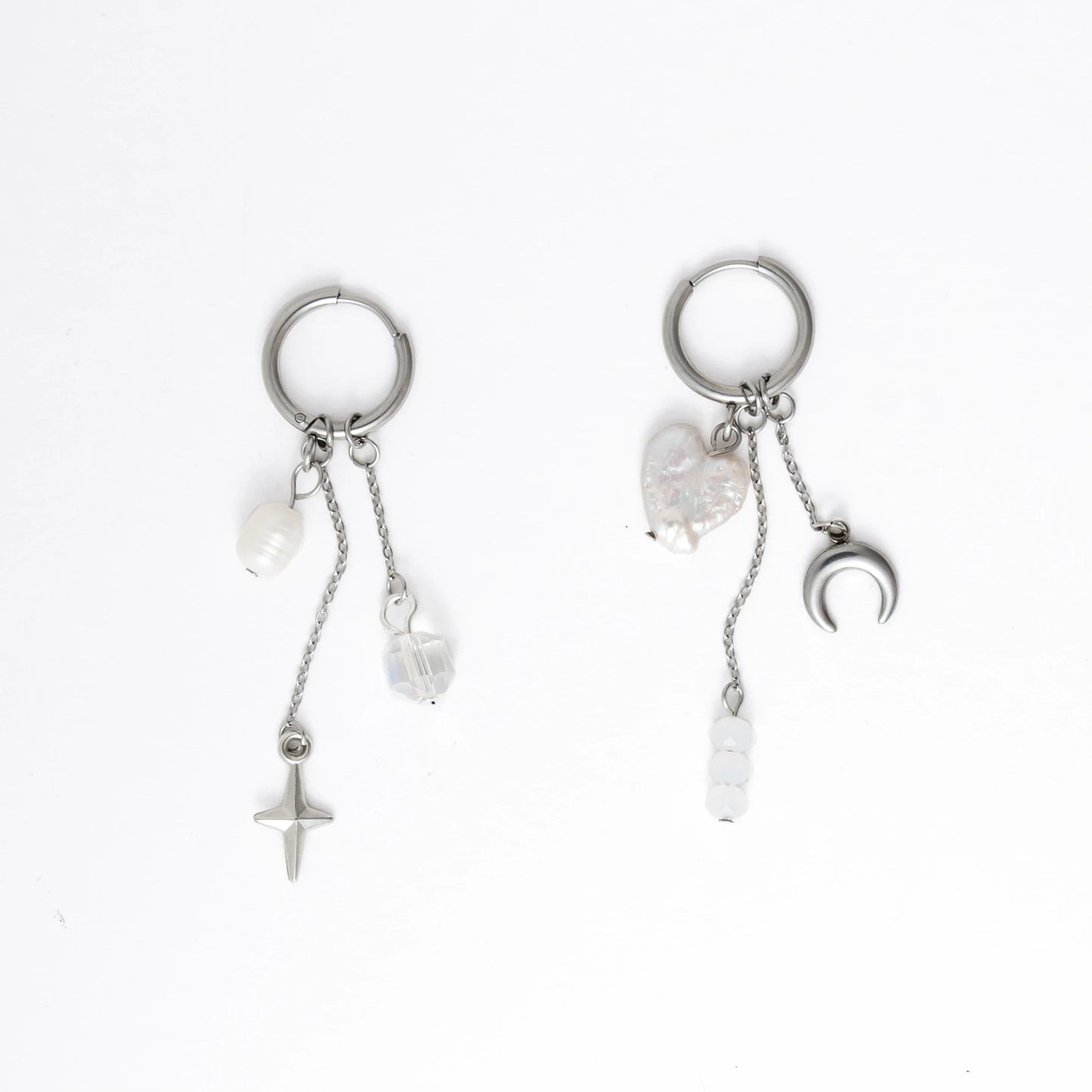Pair of silver earrings with star, moon, and heart charms on a white background