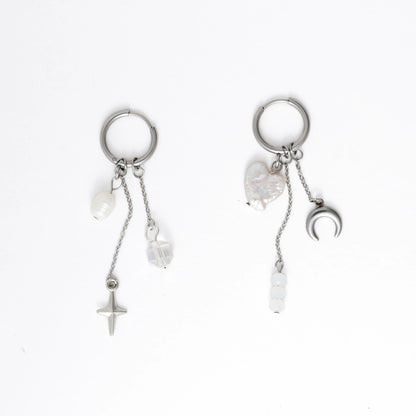 Pair of silver earrings with star, moon, and heart charms on a white background