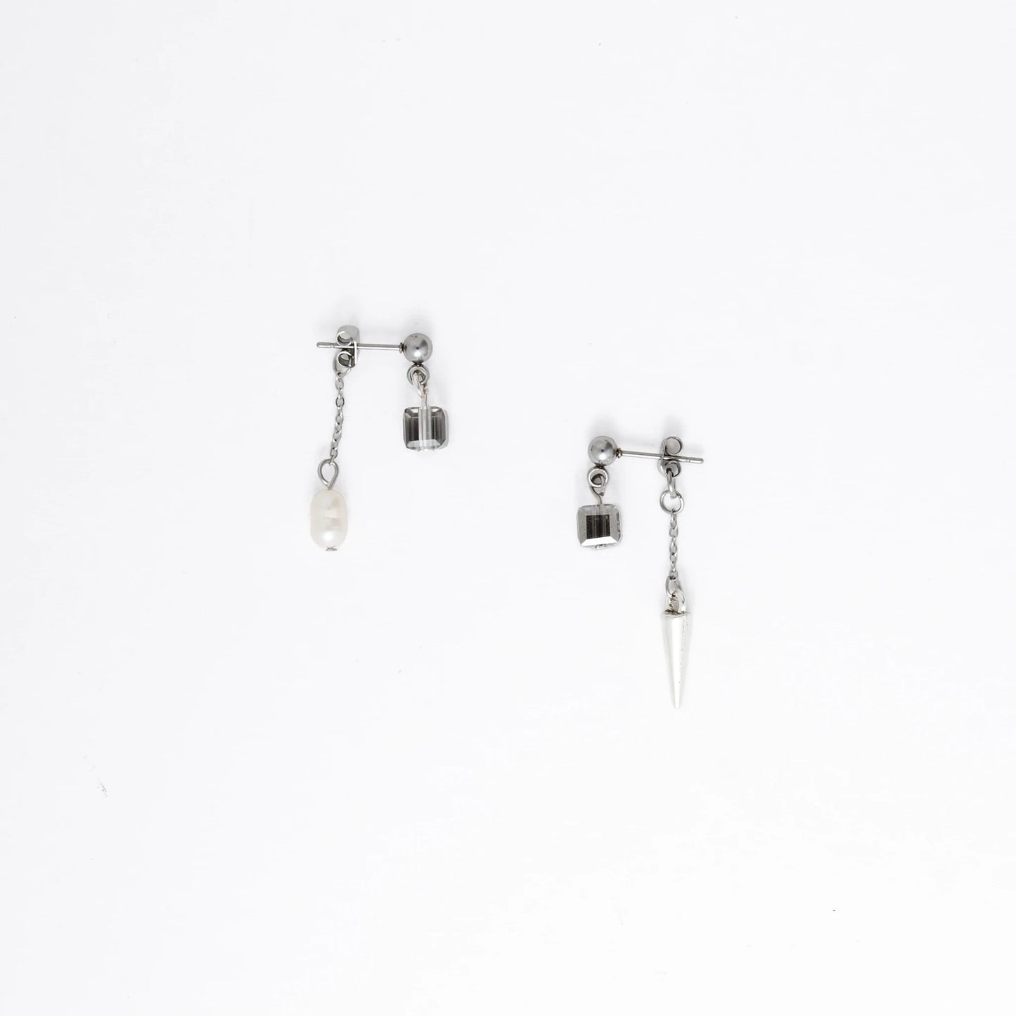 Pair of silver earrings with chain and gemstone pendants on a white background