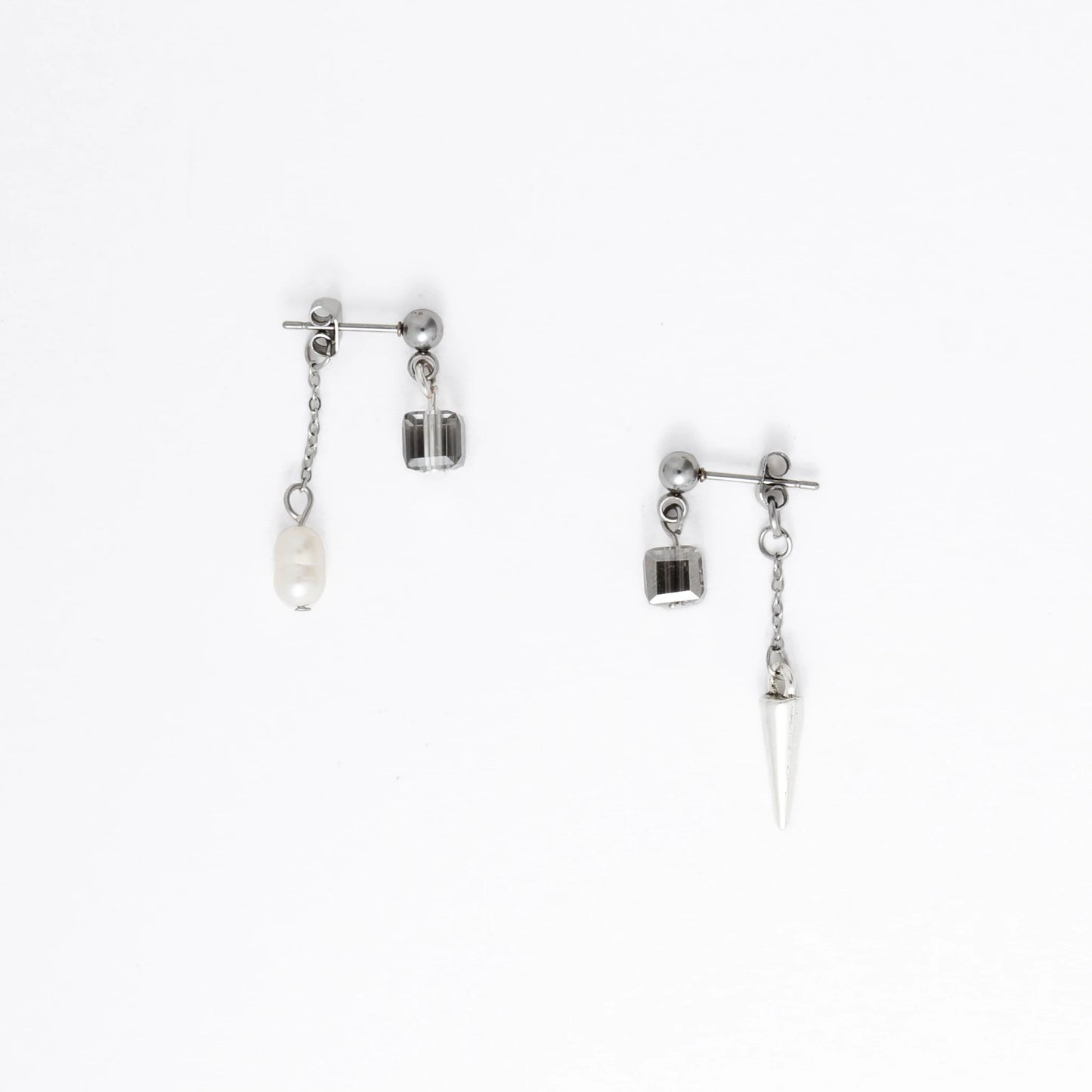 Pair of silver earrings with chain and pendant on a white background