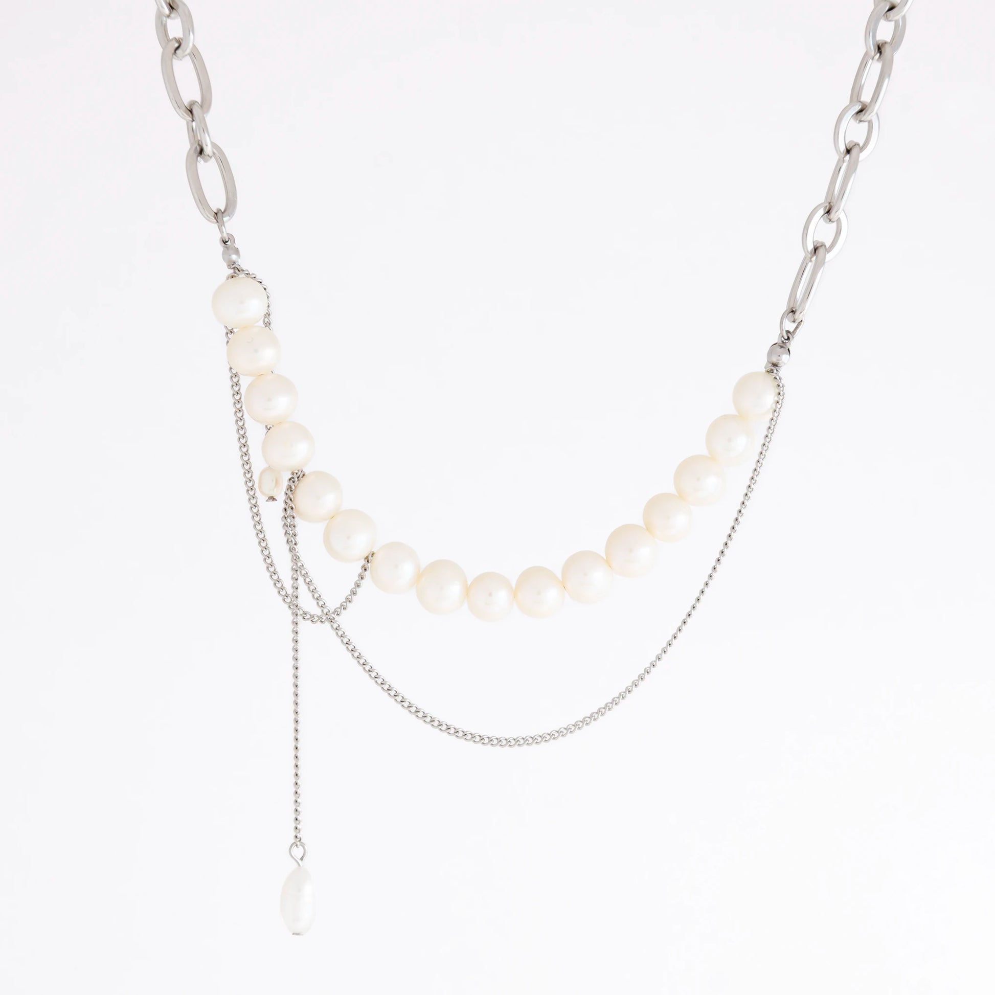 A silver-tone layered necklace featuring a curved strand of white pearls, a chunky silver chain, delicate chain drapes, and a small teardrop pearl pendant, shown on a plain white background.