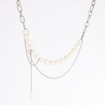A silver-tone layered necklace featuring a curved strand of white pearls, a chunky silver chain, delicate chain drapes, and a small teardrop pearl pendant, shown on a plain white background.