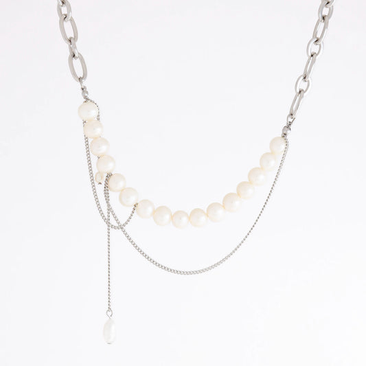 A silver-tone layered necklace featuring a curved strand of white pearls, a chunky silver chain, delicate chain drapes, and a small teardrop pearl pendant, shown on a plain white background.