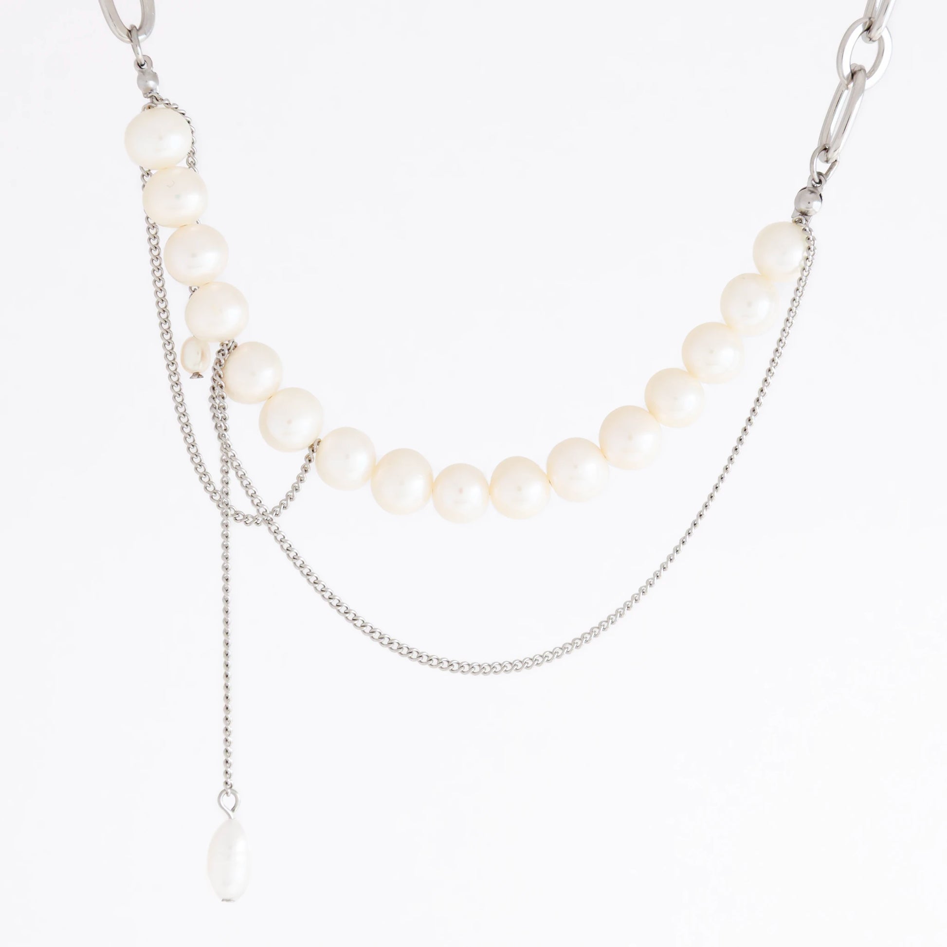A silver-tone layered necklace featuring a curved strand of white freshwater pearls, a delicate chain draped across the chest, and a long teardrop pearl pendant, shown on a plain white background.