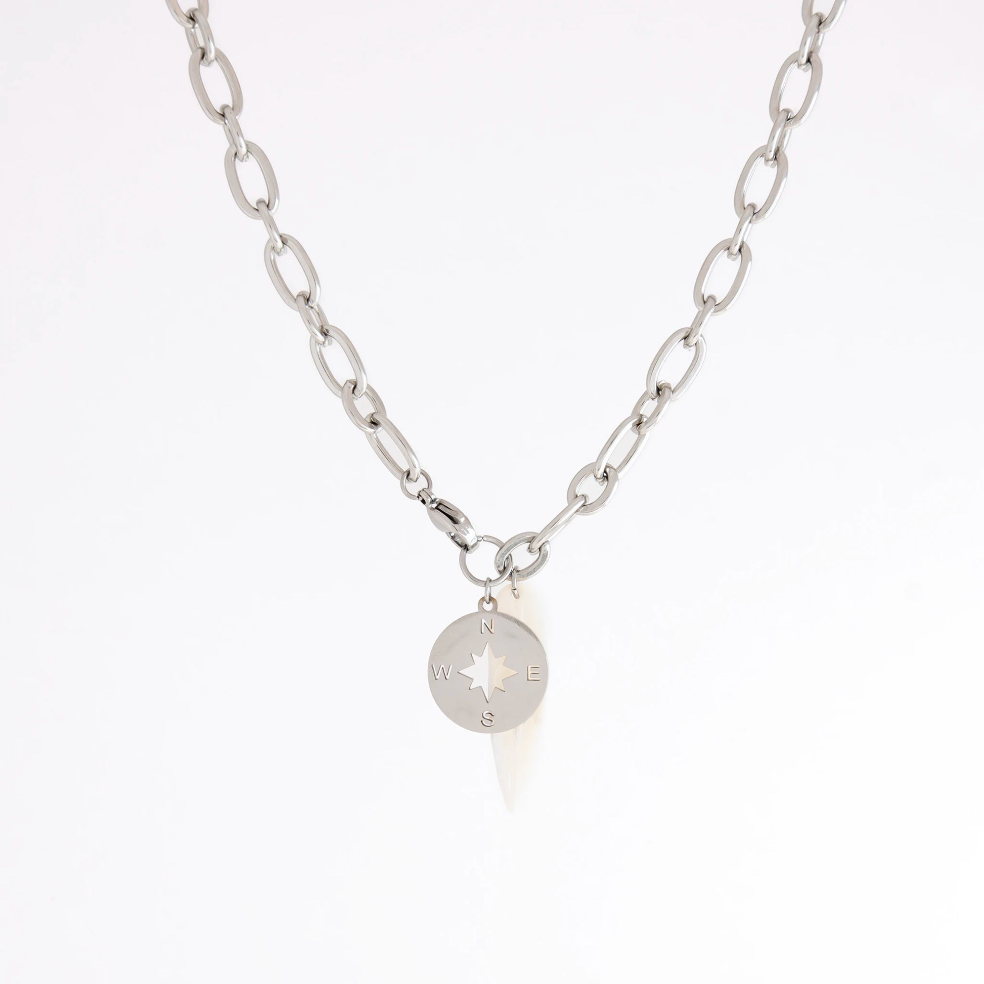 A silver chain necklace featuring a small circular compass pendant with cardinal directions, displayed against a clean white background.