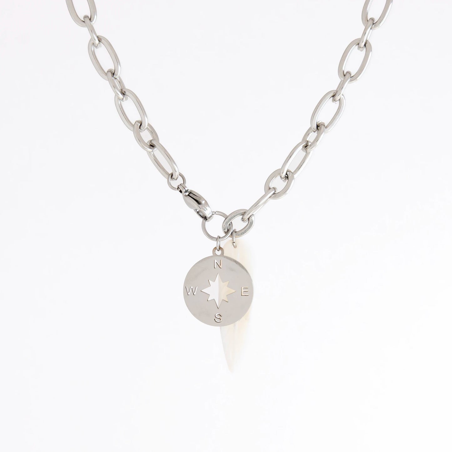 A silver chain necklace featuring a circular compass pendant with a star design and engraved N, S, E, W directions, shown on a plain white background.