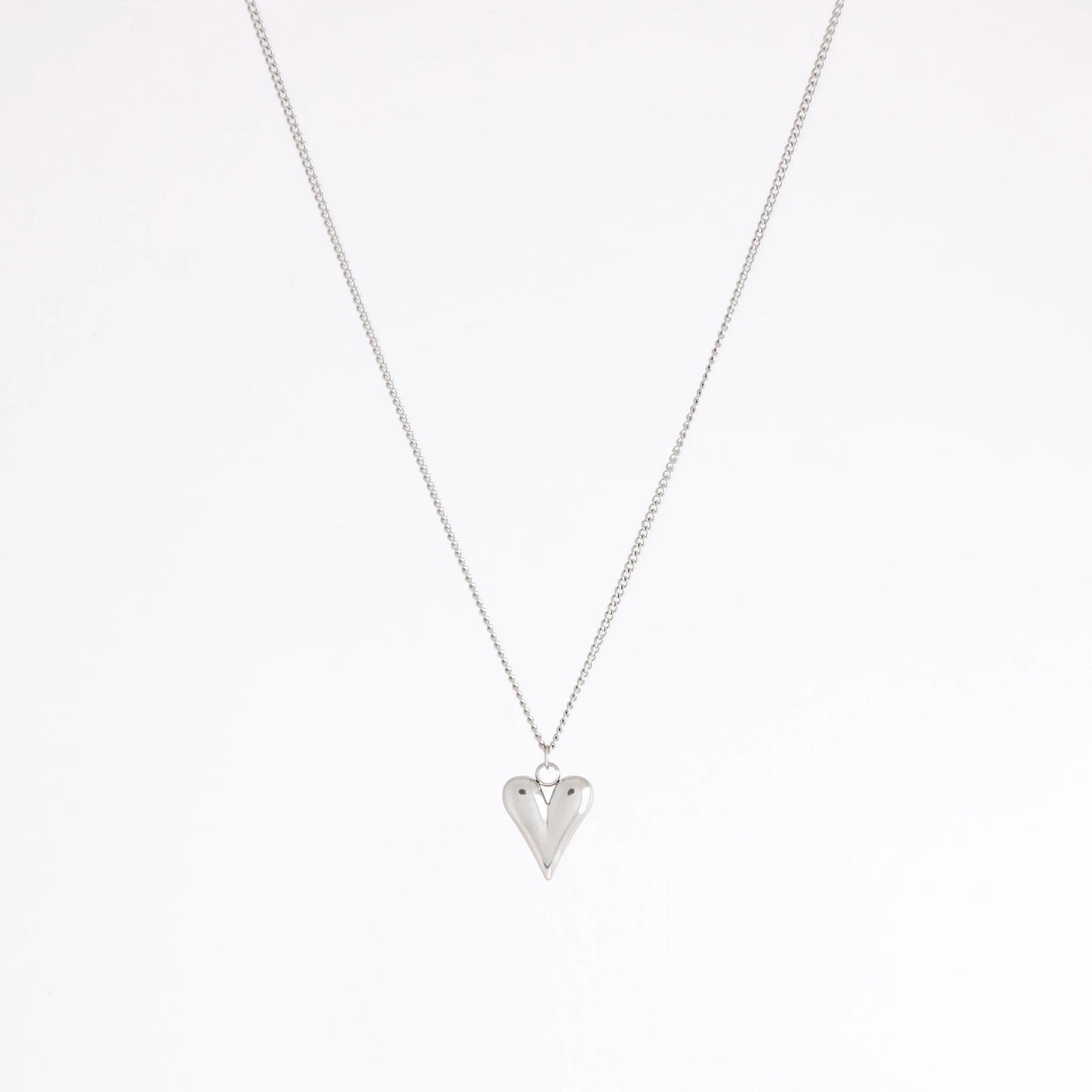A silver chain necklace with a small, polished silver heart pendant, displayed against a clean white background.