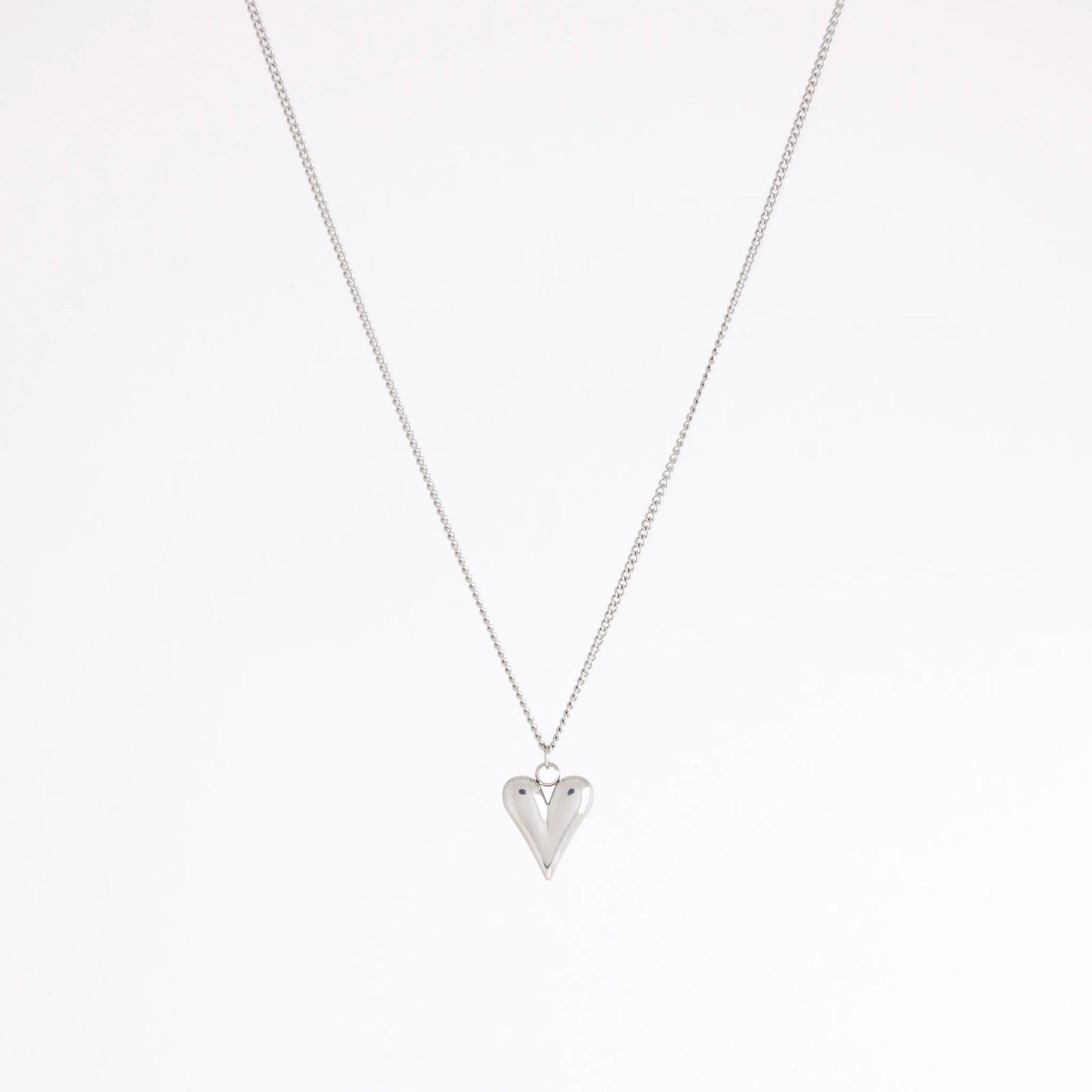 A silver chain necklace with a small, polished silver heart pendant, displayed against a clean white background.