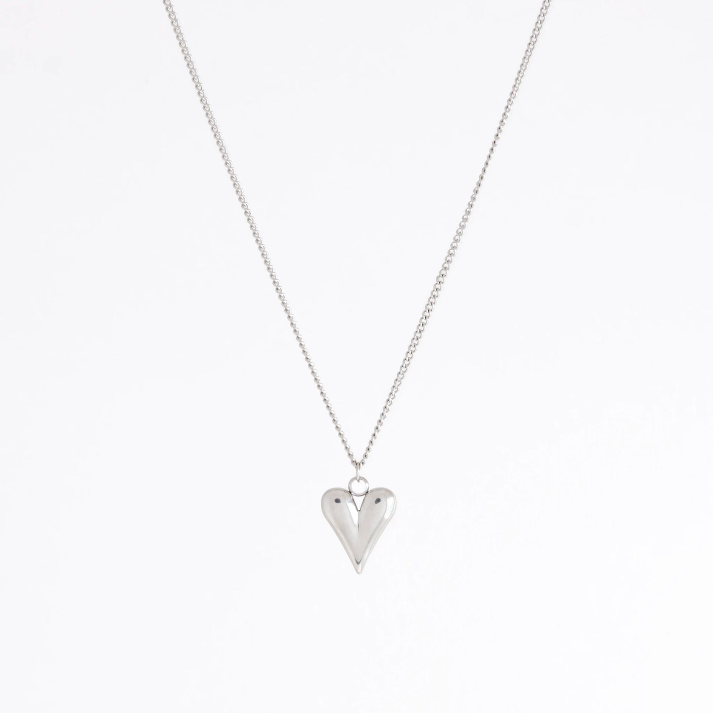 A silver heart pendant necklace on a delicate silver chain, photographed against a clean white background.