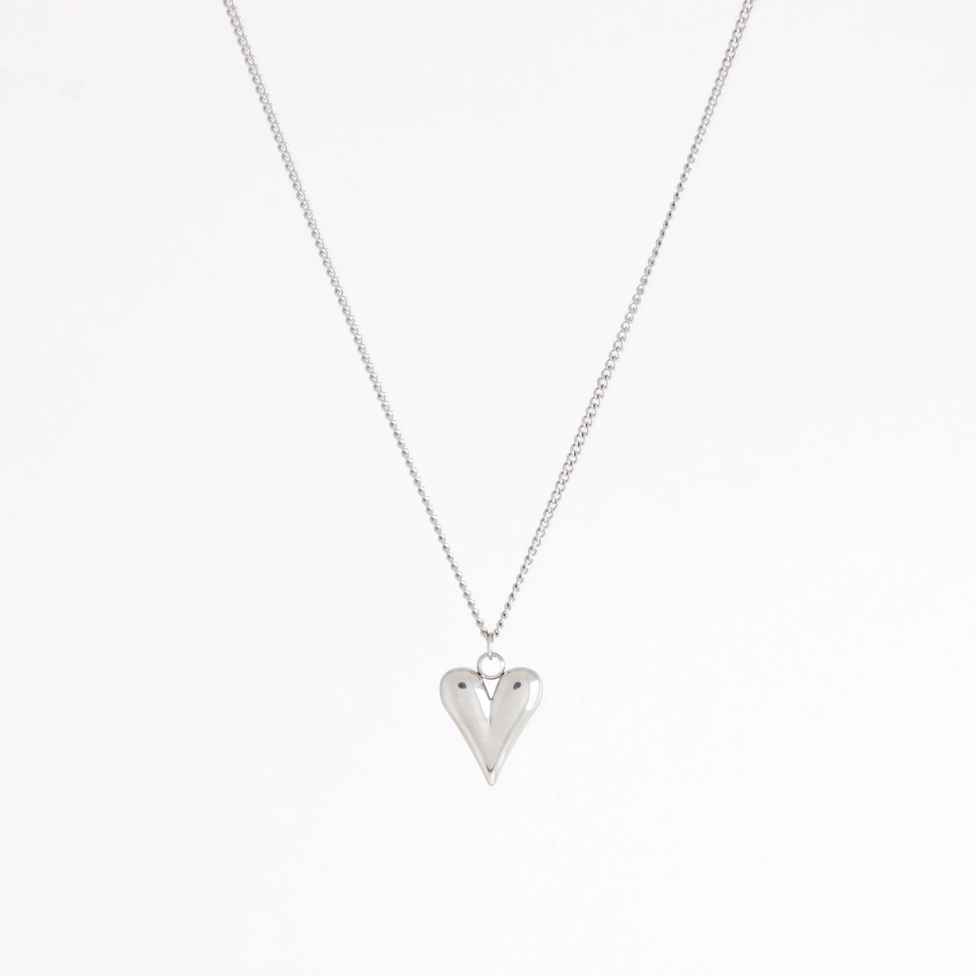 A silver heart pendant necklace on a delicate silver chain, photographed against a clean white background.