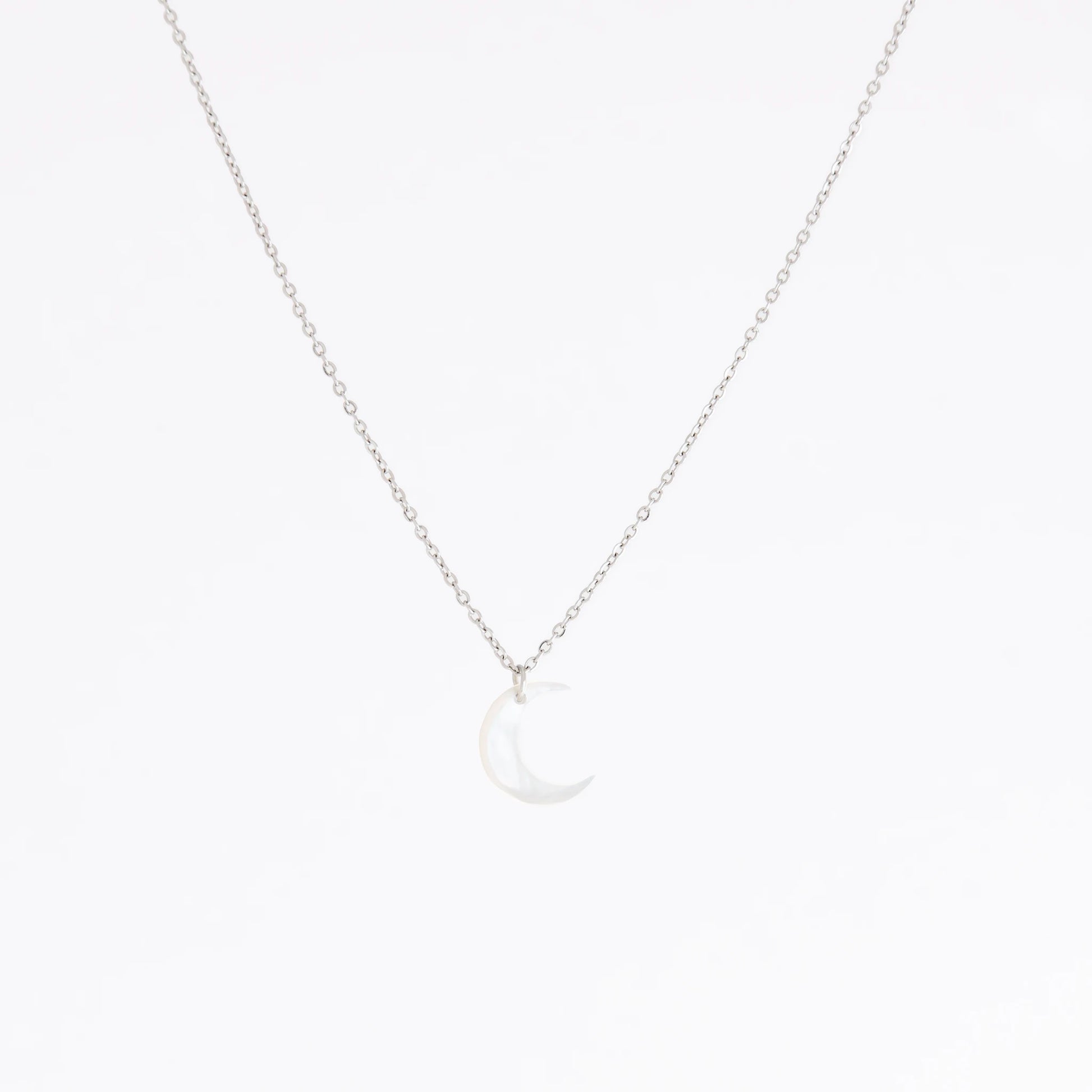 A delicate silver chain necklace featuring a small crescent moon pendant made of milky white mother-of-pearl, set against a seamless white background.