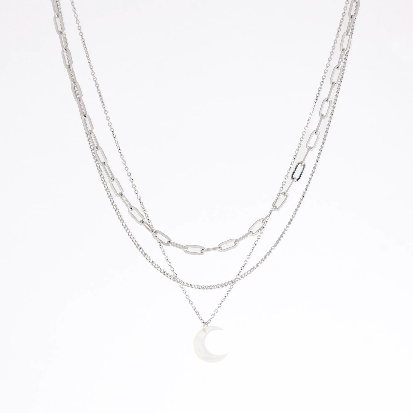 A layered silver necklace set featuring three distinct chain styles: a paperclip chain, a delicate cable chain, and a fine chain with a crescent moon pendant, displayed on a clean white background.