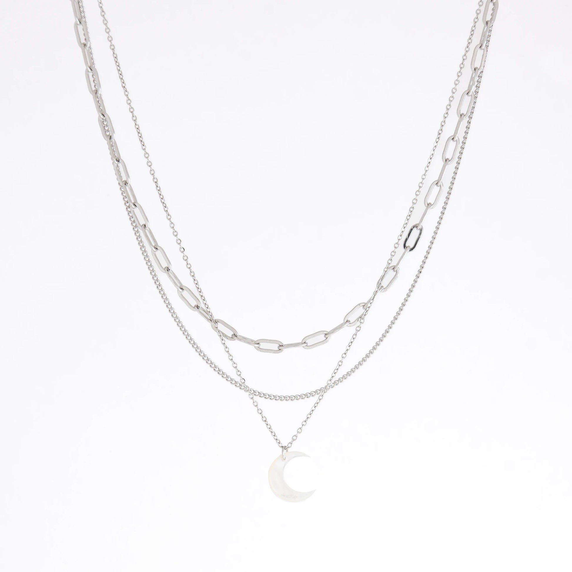 A layered silver necklace set featuring three distinct chain styles: a paperclip chain, a delicate cable chain, and a fine chain with a crescent moon pendant, displayed on a clean white background.