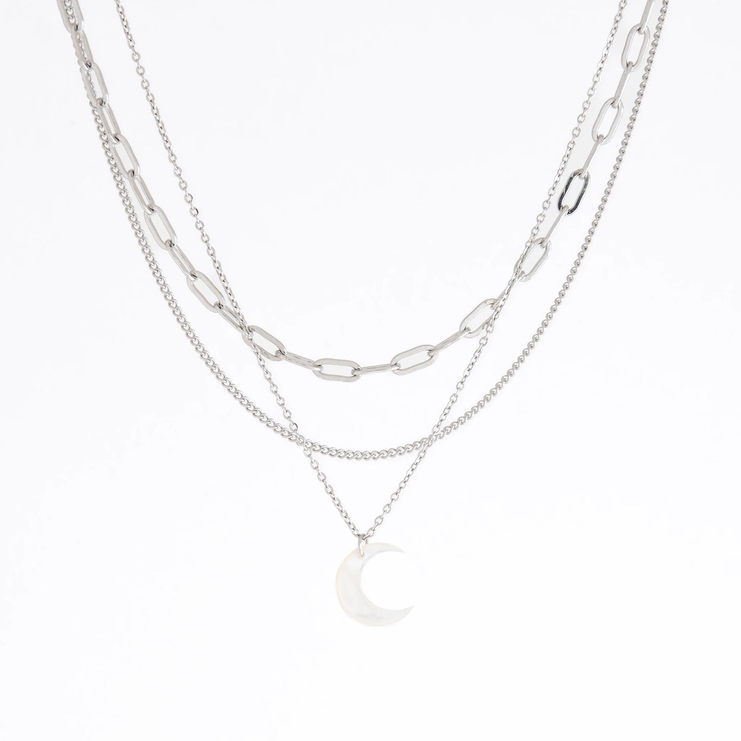 A layered silver necklace featuring a paperclip chain, a fine chain, and a small crescent moon pendant, displayed on a clean white background.