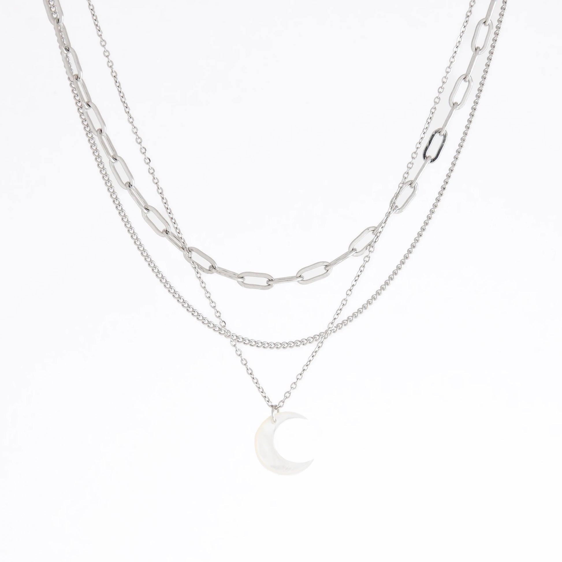 A layered silver necklace featuring a paperclip chain, a fine chain, and a small crescent moon pendant, displayed on a clean white background.