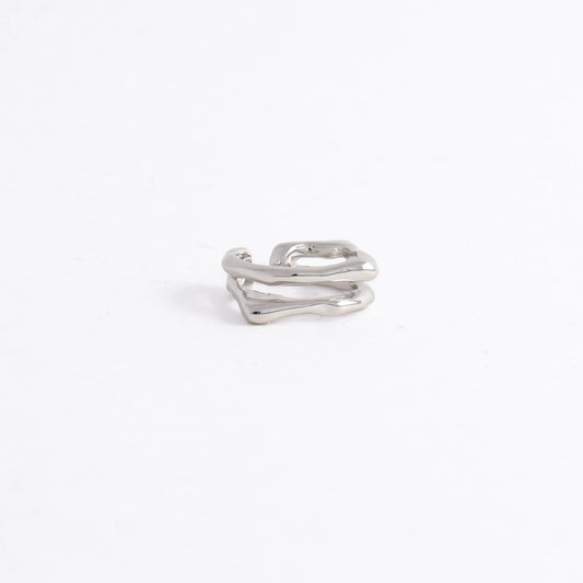 A polished silver-toned ring with an abstract, wavy, multi-layered design, photographed on a seamless white background.