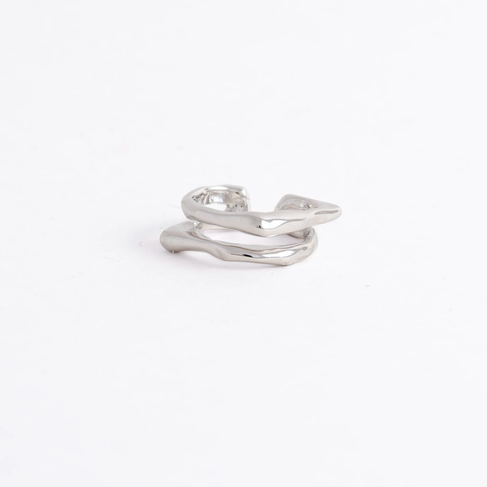 A polished silver-toned ring with an organic, wavy, multi-layered design, photographed on a seamless white background.