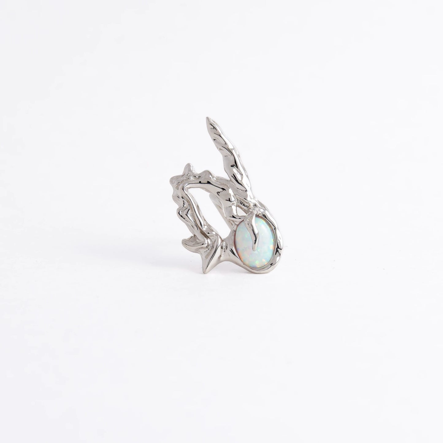 A silver ring featuring a textured, organic branch-like setting with a round iridescent opal gemstone, photographed on a seamless white background.