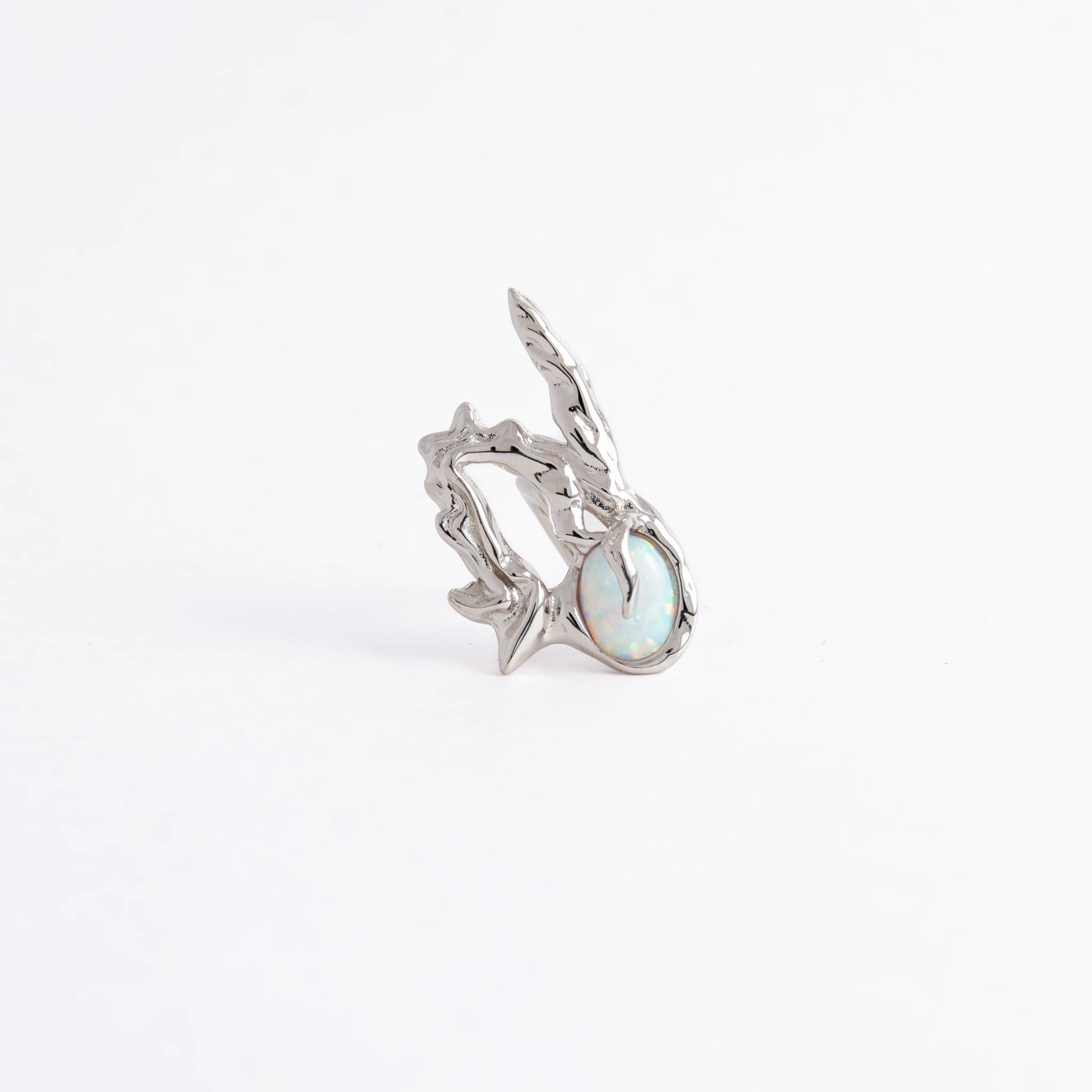 A silver ring featuring a textured, organic branch-like setting with a round iridescent opal gemstone, photographed on a seamless white background.