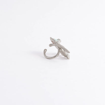 A silver-toned ring shaped like a stylized leaf with a curved hook-like base, photographed on a plain white background.