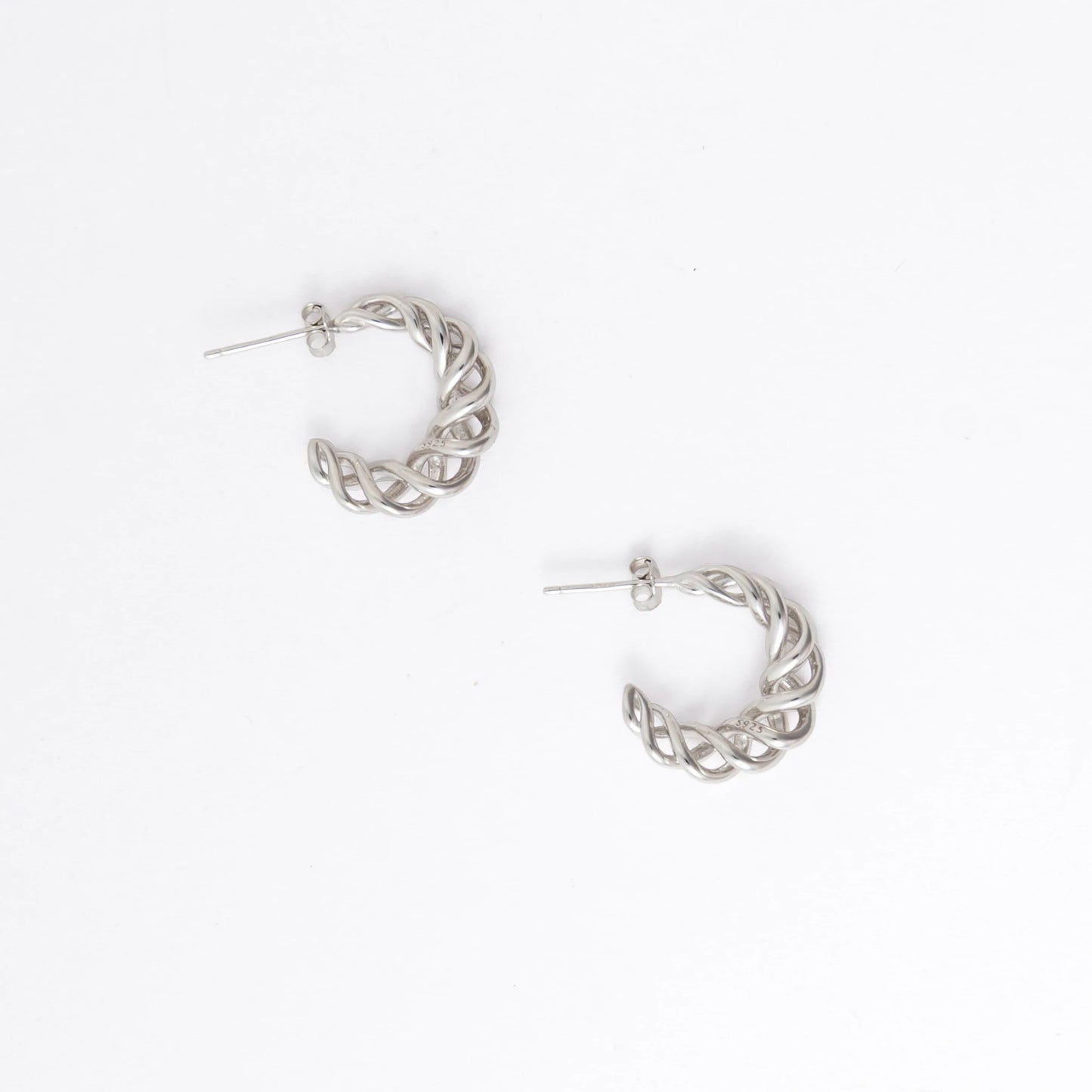 A pair of silver-toned twisted half-hoop earrings with post backs, displayed on a clean white background.