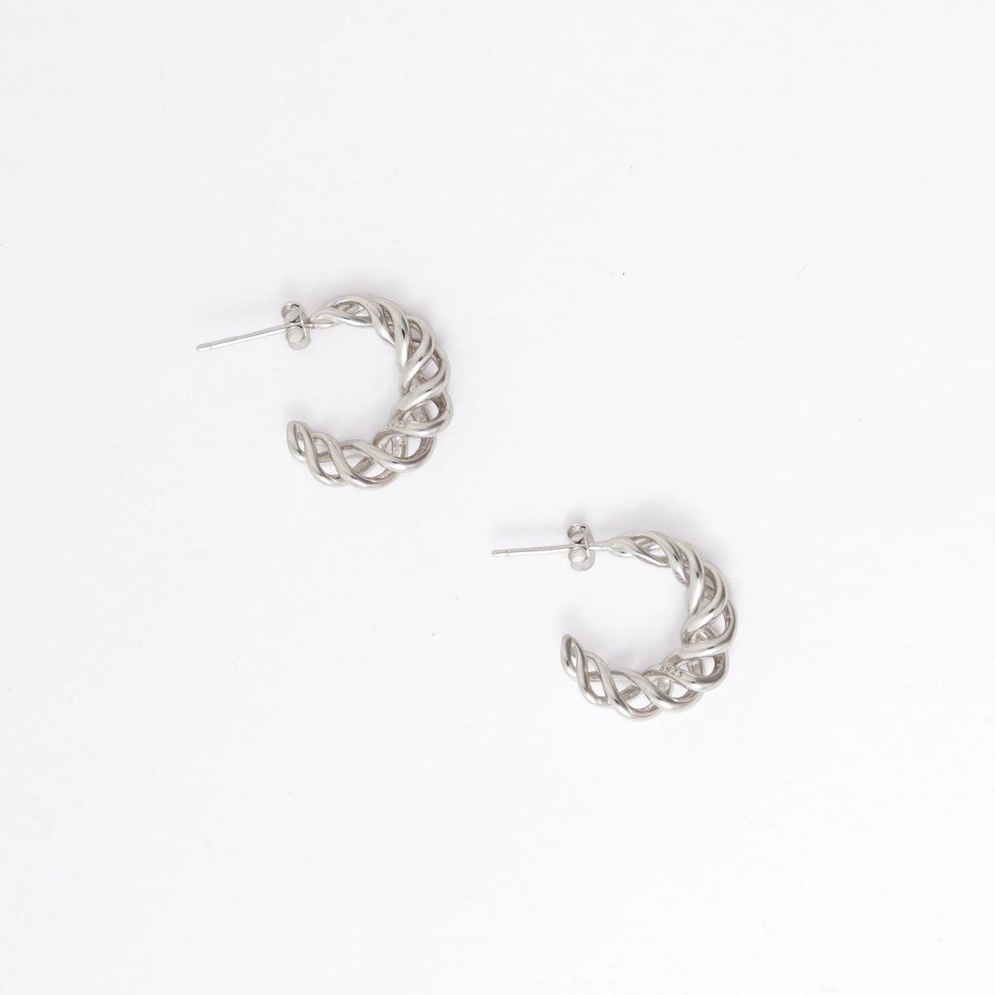 A pair of silver twisted half-hoop earrings on a clean white background.