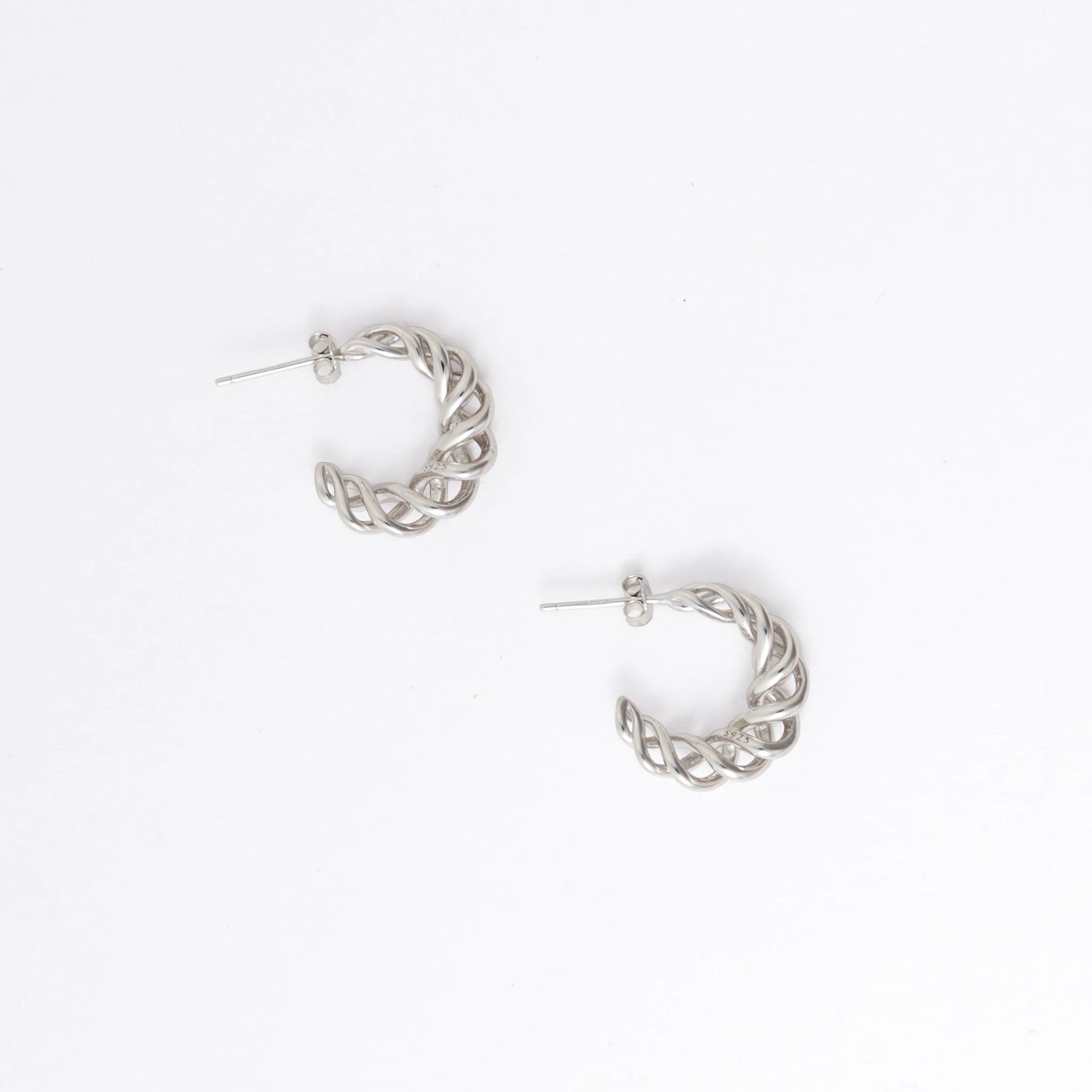 A pair of silver twisted half-hoop earrings on a clean white background.