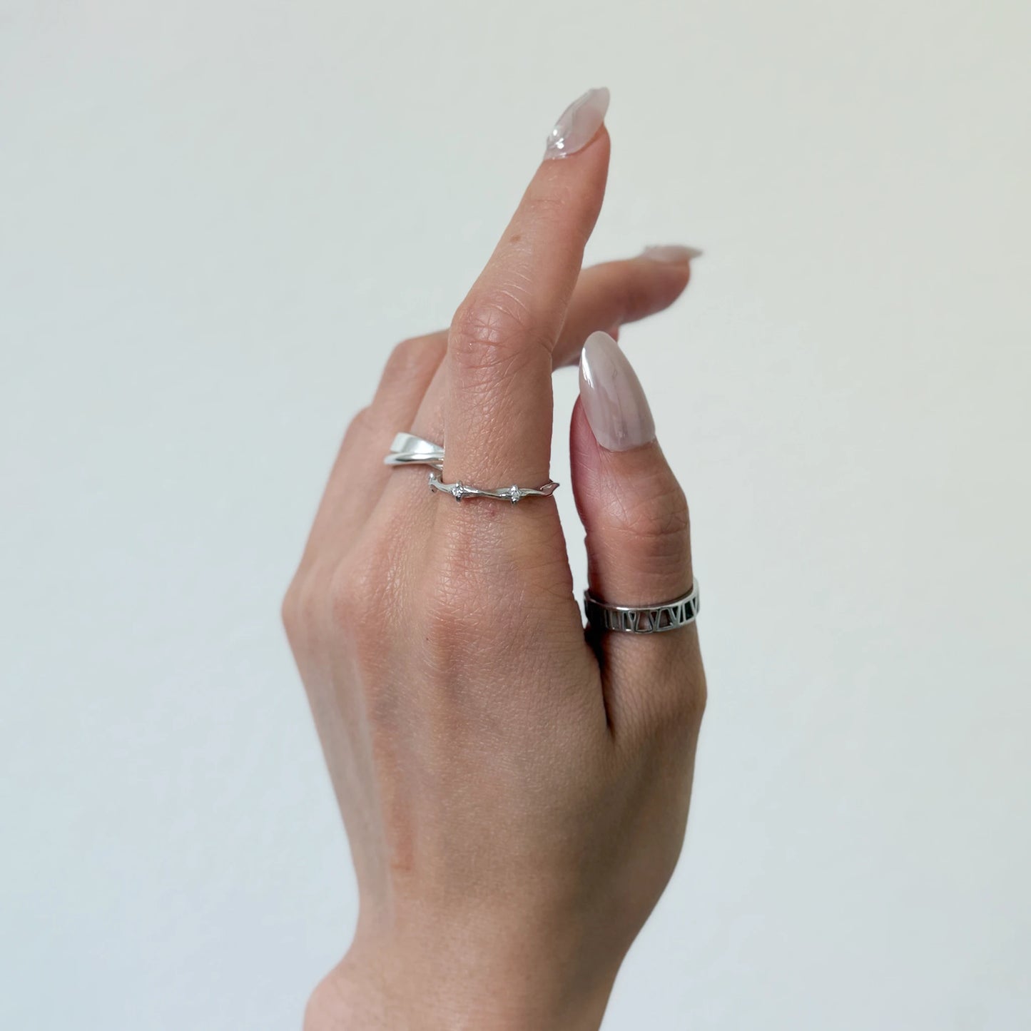 Sterling silver stackable rings with a starling band ring and geometric ring on a gray background