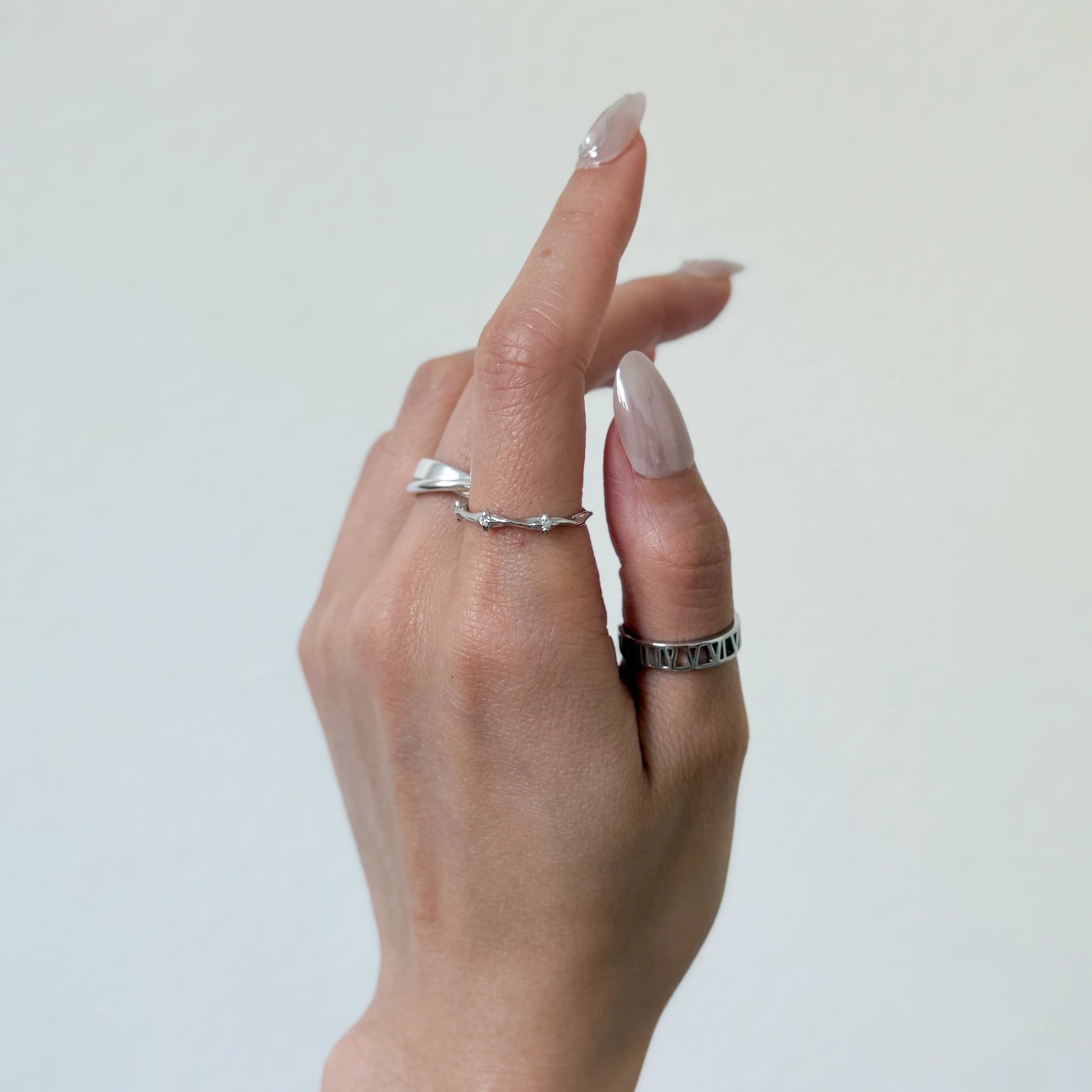 Sterling silver stackable rings with a starling band ring and geometric ring on a gray background