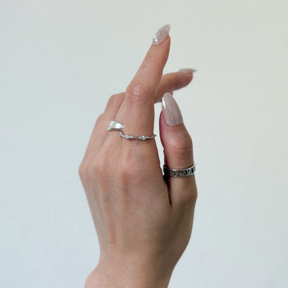 Sterling silver stackable rings with a starling band ring and geometric ring on a gray background