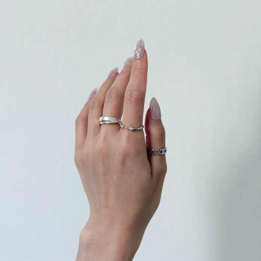 Sterling silver stackable rings with a starling band ring and geometric ring on a gray background
