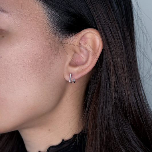 Silver bar stud earrings worn by model on a gray background