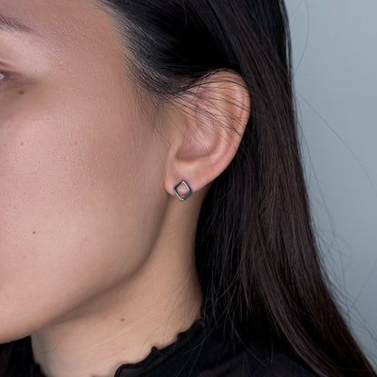 Silver square earrings worn by model on a gray background